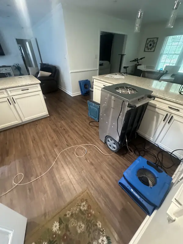 Dehumidifier and blue air movers set up on the floor beside bathroom vanities